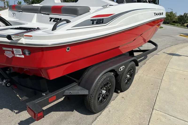 Slide: The Image of Red and white 2027 Tahoe T21 boat on a trailer, parked outdoors. - 7