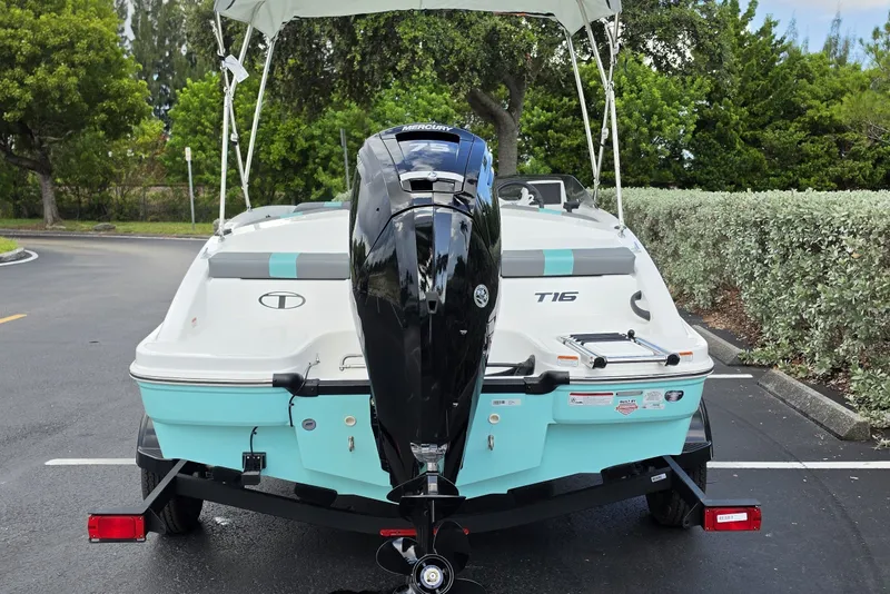 Slide: The Image of 2027 Tahoe T16 boat with outboard motor, parked on a paved area surrounded by greenery. - 10