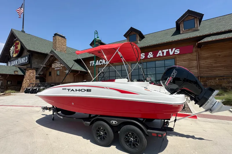 The Image of Red and white 2027 Tahoe 1950 boat on trailer outside outdoor store. - 0