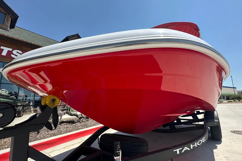 Slide: The Image of Red 2027 Tahoe 1950 boat on trailer, parked outside a building under clear blue sky. - 4