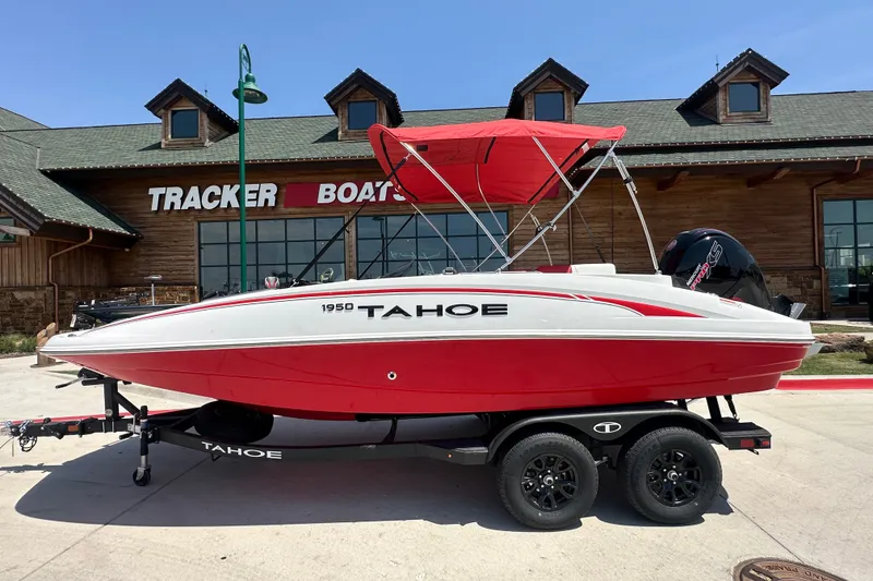 Slide: The Image of Red and white 2027 Tahoe 1950 boat on trailer outside Tracker Boats store. - 1