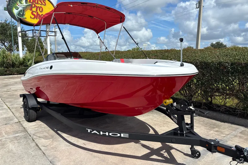 Slide: The Image of 2027 Tahoe T18 boat with red hull and canopy on trailer, parked outdoors. - 5