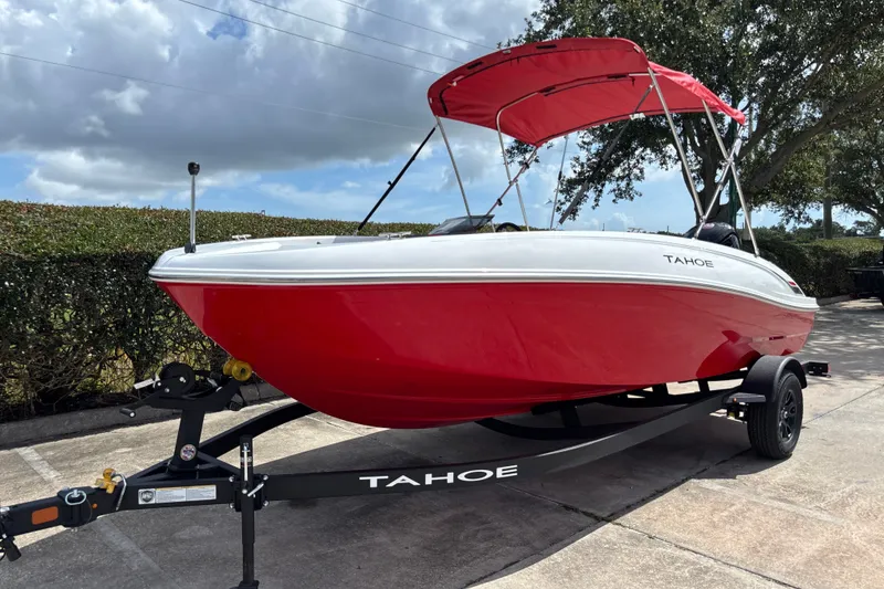 Slide: The Image of Red 2027 Tahoe T18 boat on trailer with canopy, parked outdoors under cloudy sky. - 1