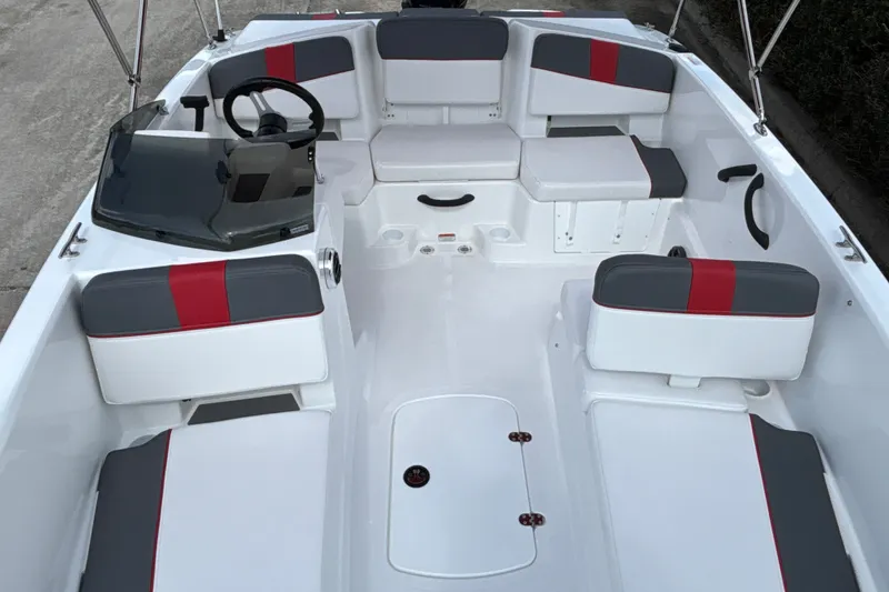 Slide: The Image of 2027 Tahoe T18 boat interior with gray and red seating, steering wheel, and storage compartments. - 7