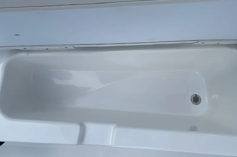 Slide: The Image of 2027 Tahoe T18 boat storage compartment with drain plug, white interior. - 20