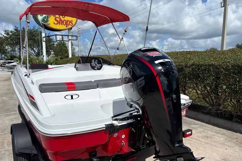 Slide: The Image of 2027 Tahoe T18 boat with Mercury 115 outboard motor, parked near a shop sign. - 3