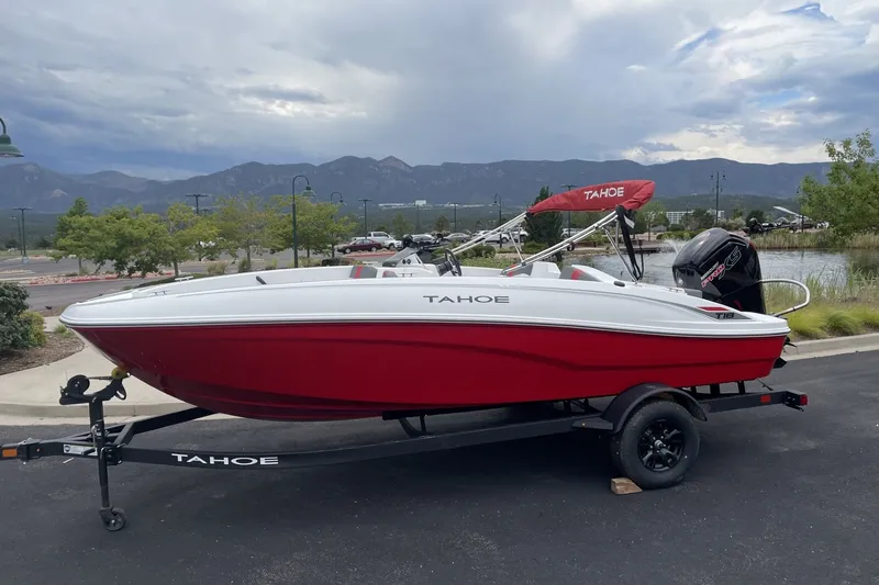 The Image of 2027 Tahoe T18 boat with red hull on trailer, parked outdoors with scenic mountain backdrop. - 0