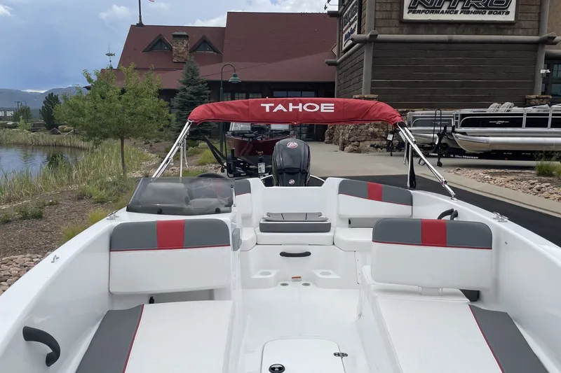 Slide: The Image of 2027 Tahoe T18 boat with red canopy, docked near a rustic building. - 4