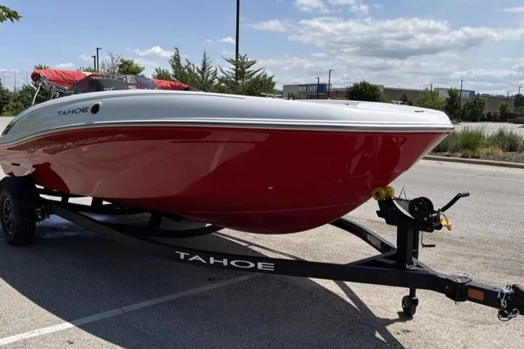 Slide: The Image of 2027 Tahoe T18 boat with red hull on trailer in parking lot. - 2