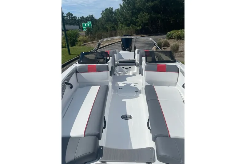 Slide: The Image of 2027 Tahoe T21 boat interior with gray and red seating, parked outdoors. - 2