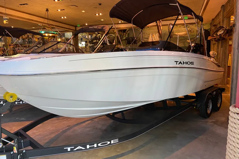 Slide: The Image of 2027 Tahoe T21 boat on trailer in showroom, featuring sleek white design. - 1
