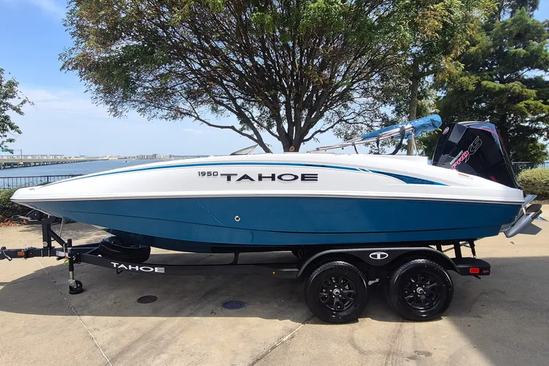 The Image of Blue and white 2027 Tahoe 1950 boat on trailer by waterfront. - 0