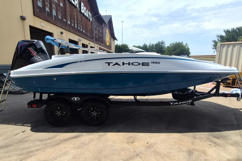 Slide: The Image of 2027 Tahoe 1950 boat on trailer, parked outside a building under clear skies. - 4
