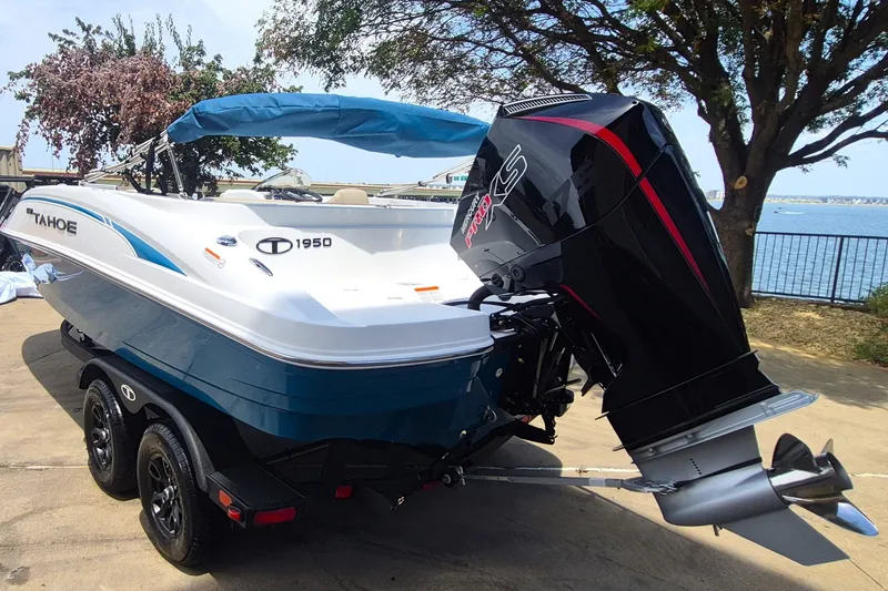 Slide: The Image of 2027 Tahoe 1950 boat with powerful outboard motor, parked near a scenic waterfront. - 7