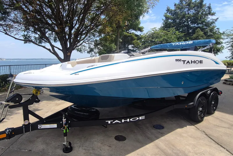 Slide: The Image of 2027 Tahoe 1950 boat on trailer by lakeside, featuring sleek blue and white design. - 1