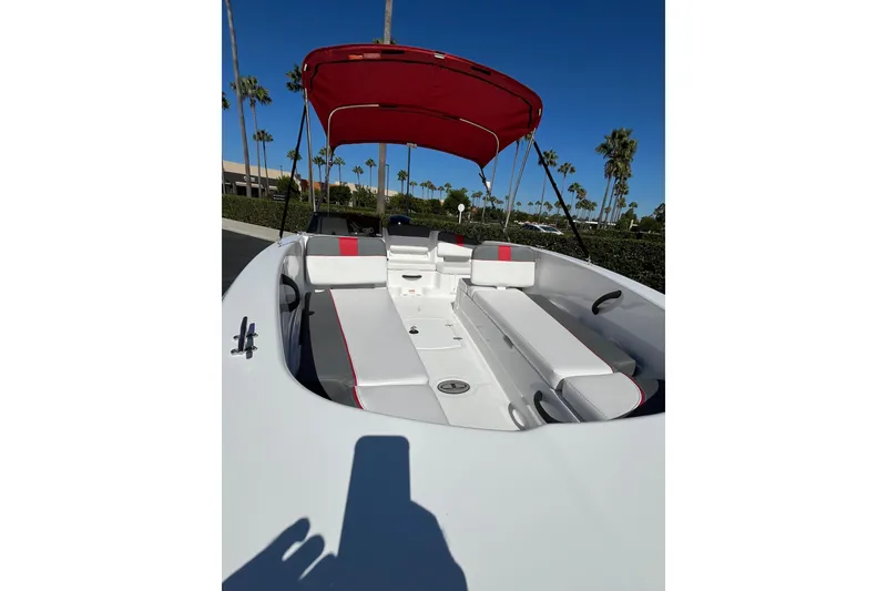 Slide: The Image of 2027 Tahoe T18 boat with red canopy and white seating, parked outdoors. - 7