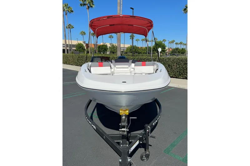 Slide: The Image of 2027 Tahoe T18 boat with red canopy on trailer in sunny parking lot. - 2