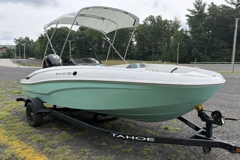 Slide: The Image of 2027 Tahoe T18 boat with canopy on trailer, parked outdoors. - 2