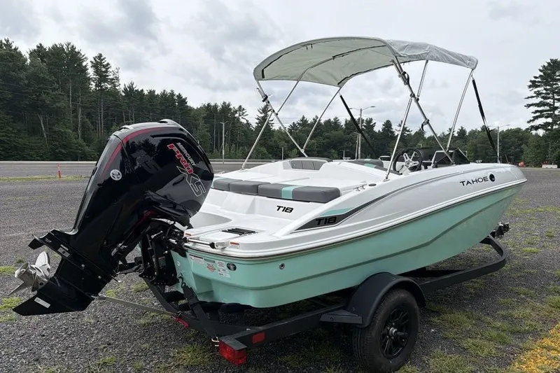 Slide: The Image of 2027 Tahoe T18 boat with canopy and outboard motor on a trailer, parked outdoors. - 4