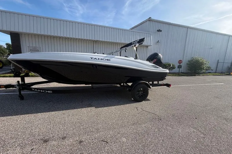Slide: The Image of 2027 Tahoe T18 boat on trailer, parked outside a large white building. - 73