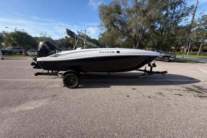 Slide: The Image of 2027 Tahoe T18 boat on trailer in parking lot, sunny day, trees in background. - 1