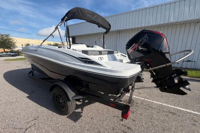 Slide: The Image of 2027 Tahoe T18 boat with Mercury engine, parked outdoors on a sunny day. - 2