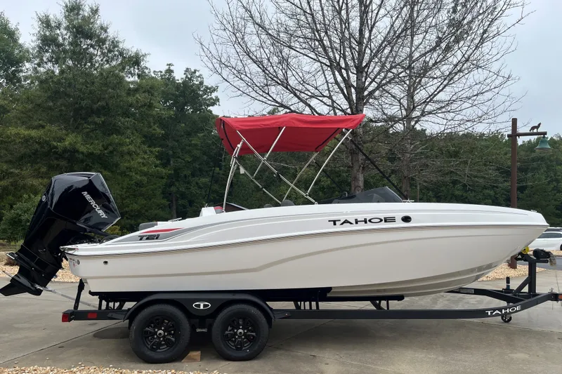 Slide: The Image of 2027 Tahoe T21 boat with red canopy on trailer, parked outdoors. - 1