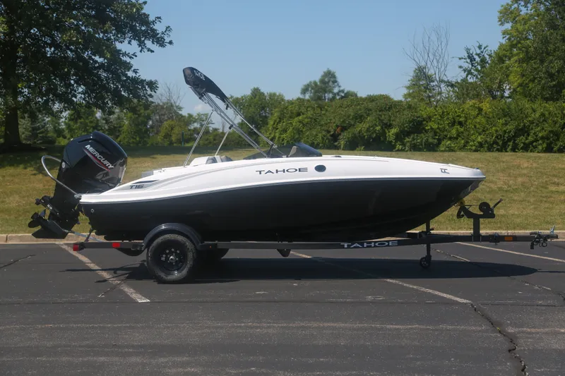 The Image of 2027 Tahoe T16 boat on trailer, parked outdoors, featuring sleek design and Mercury outboard motor. - 0