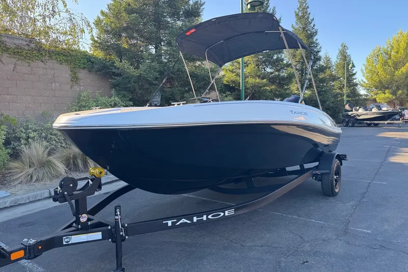 Slide: The Image of 2027 Tahoe T18 boat on trailer, parked outdoors with trees in background. - 2