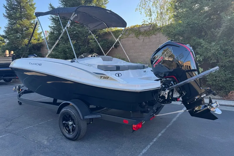 Slide: The Image of 2027 Tahoe T18 boat with canopy and powerful outboard motor, parked outdoors. - 1