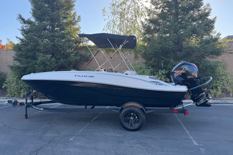 The Image of 2027 Tahoe T18 boat with canopy and outboard motor, parked outdoors. - 0