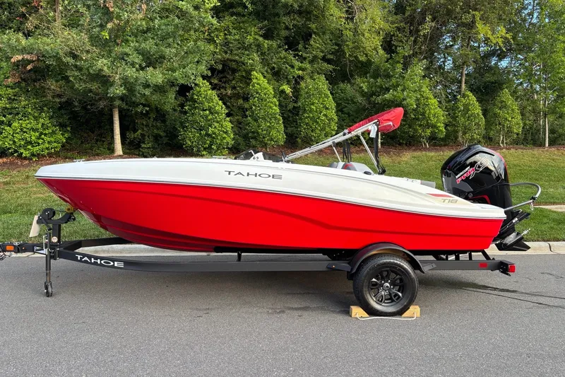 The Image of Red 2027 Tahoe T18 boat on trailer, parked on road with lush greenery background. - 0