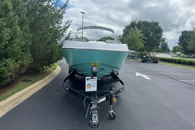 Slide: The Image of 2027 Tahoe T21 boat on trailer in parking lot, surrounded by trees and cloudy sky. - 2