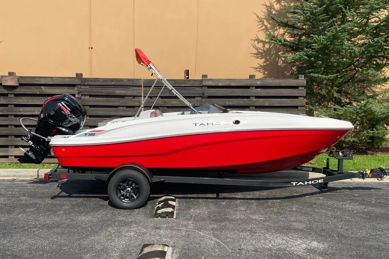 The Image of 2027 Tahoe T18 boat in red and white on a trailer, parked outdoors. - 0