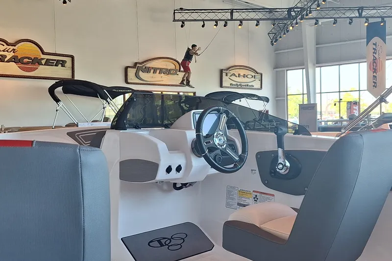 Slide: The Image of Interior of a 2027 Tahoe T21 boat in a showroom with steering wheel and seating. - 2