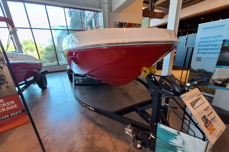 Slide: The Image of 2027 Tahoe T21 boat on display in showroom, featuring sleek red and white design. - 1