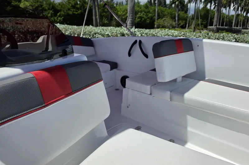 Slide: The Image of Interior of 2027 Tahoe T16 boat with red and gray seating, lush greenery background. - 69