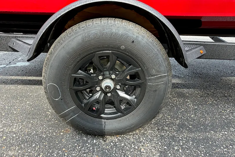 Slide: The Image of Black wheel of a 2027 Tahoe T18 trailer on asphalt. - 24