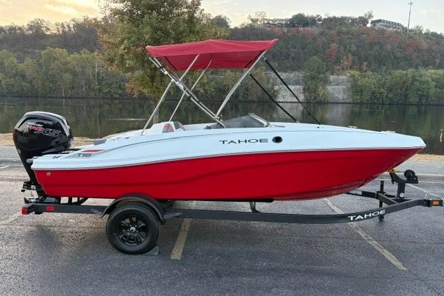Slide: The Image of 2027 Tahoe T18 boat with red hull and canopy on a trailer by a river. - 4