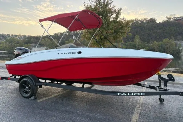 Slide: The Image of 2027 Tahoe T18 boat with red hull and canopy on a trailer, parked outdoors. - 2
