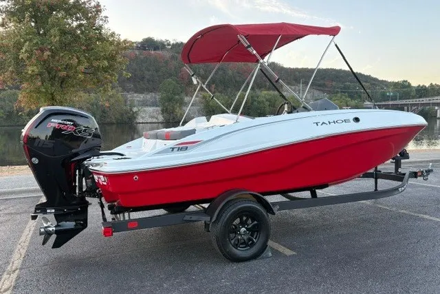 Slide: The Image of 2027 Tahoe T18 boat with red hull and canopy on a trailer by a river. - 10