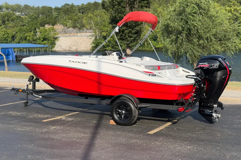 Slide: The Image of 2027 Tahoe T18 boat with red and white design, parked near a lake. - 2