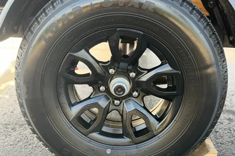 Slide: The Image of 2027 Tahoe T18 black alloy wheel with Loadstar tire on asphalt surface. - 12