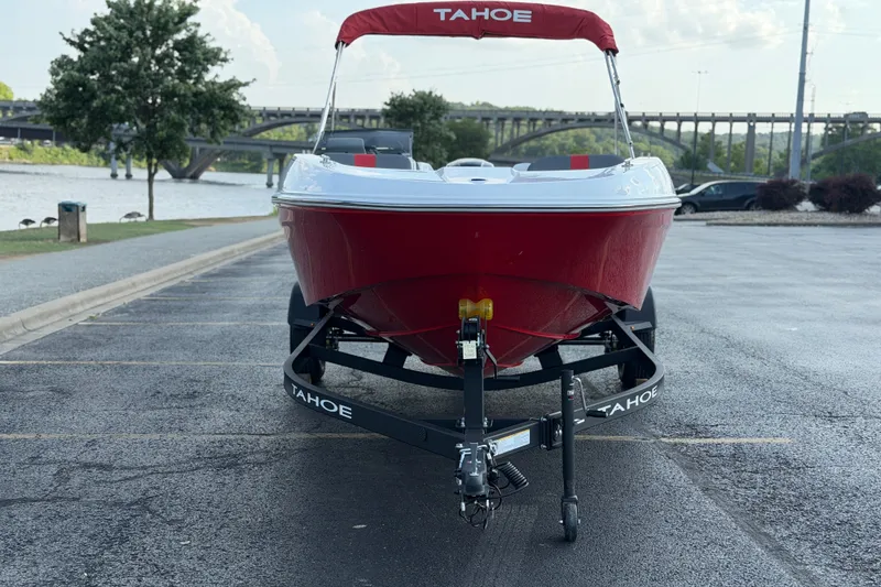 Slide: The Image of Red 2027 Tahoe T18 boat on trailer, parked near a river with a bridge. - 10