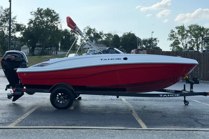 Slide: The Image of 2027 Tahoe T18 boat in red and white on a trailer, parked outdoors. - 8