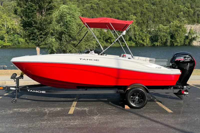 Slide: The Image of 2027 Tahoe T18 boat with red hull and canopy, parked near a scenic lake. - 1