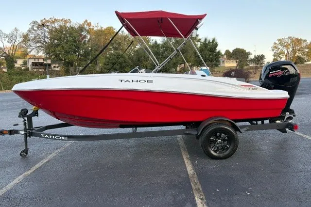 Slide: The Image of 2027 Tahoe T18 boat with red hull and canopy on trailer in parking lot. - 1