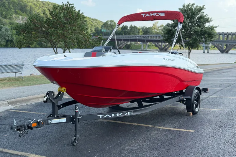 Slide: The Image of 2027 Tahoe T18 boat in vibrant red on trailer by riverside parking. - 11