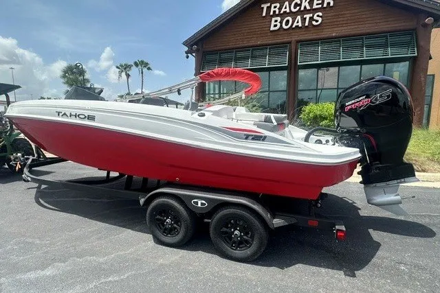 Slide: The Image of 2027 Tahoe T21 boat with red hull on trailer outside Tracker Boats dealership. - 1