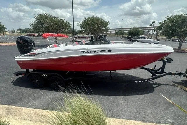 Slide: The Image of 2027 Tahoe T21 boat in red and white on a trailer, parked outdoors. - 2
